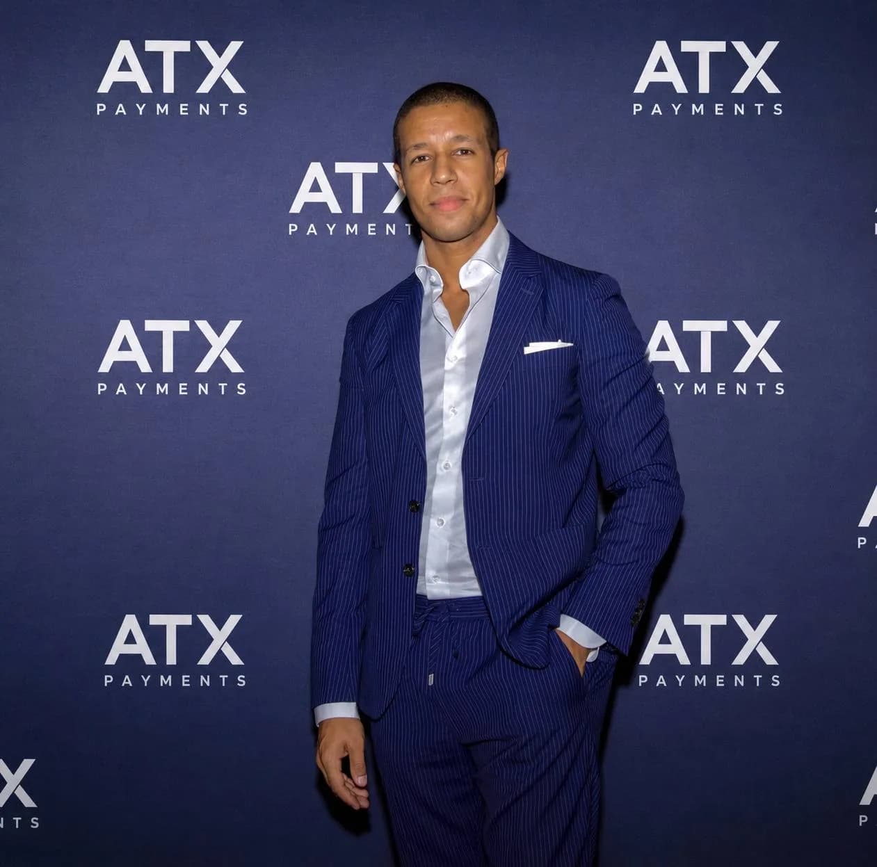 A business professional in a tailored navy pinstripe suit before an ATX Payments backdrop.